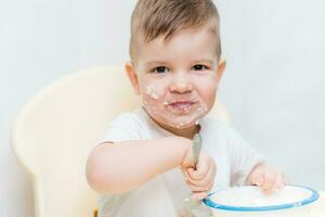 adorable baby boy eats porridge with a small spoon himself photo