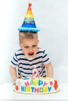 pequeño niño golpes un vela en el pastel en su cumpleaños foto