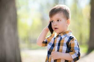 hermosa bebé habla en el teléfono en naturaleza foto