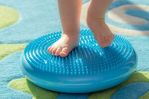 little kid massages his feet while standing on the rug photo