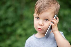 beautiful baby speaks on the phone on the street photo