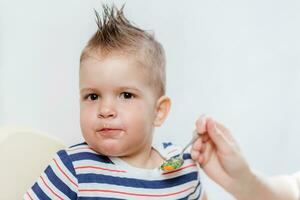 mom feeds her little baby with a spoon photo