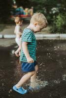 pequeño chico saltando en un charco en verano foto