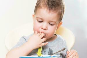 the kid eats buckwheat porridge in the kitchen photo