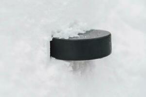 hockey puck lies on the snow close-up photo