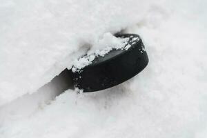 hockey puck lies on the snow close-up photo