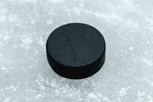 hockey puck lies on the snow close-up photo