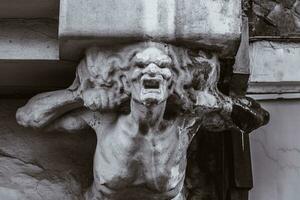 bust of concrete of a terrible woman on the facade of an old house photo