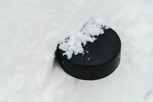 hockey puck lies on the snow close-up photo