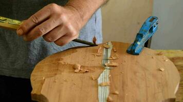 Luthier working with a chisel in workplace video