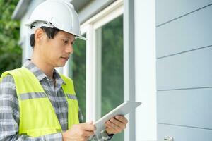 inspector or engineer is inspecting construction and quality assurance new house using a tablet. Engineers or architects or contactor work to build the house before handing it over to the homeowner photo