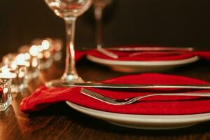 Christmas table setting. Plate and cutlery on napkin. Preparing for festive dinner. Candles burning on table on Christmas Eve. photo