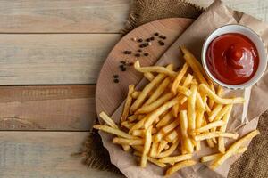 Hot golden french fries with ketchup on a wooden background. Tasty american fast food. photo