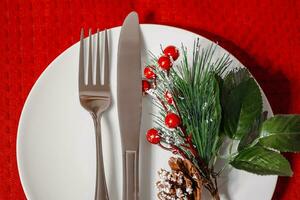 Christmas table setting. Plate and cutlery on red napkin. Decoration for a festive dinner. photo