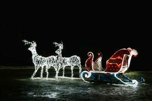 Glowing Christmas reindeer and sleigh of Santa Claus. Street New Year decor. photo