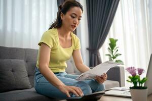 Woman using calculator to check total sum of household bills photo