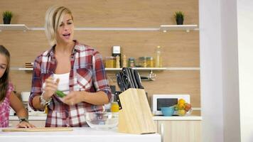 Mother at the kitchen cutting a cucumber next to her young daughter video