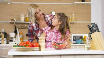 amorevole madre aiuta sua figlia per mescolare un' insalata nel un' bicchiere ciotola a il cucina. lento movimento metraggio video
