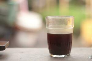 photo of a glass of black coffee in the morning with a blurred background