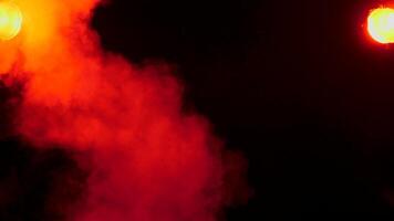 Clouds of abstract smoke over red lights on a black background video