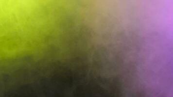 Green and purple abstract smoke flying over a black background in studio video