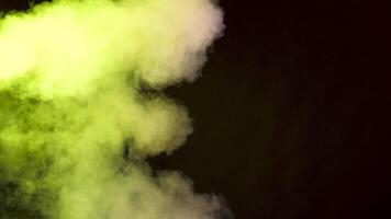 Dense abstract and dynamic smoke colorful clouds over a black background in studio video