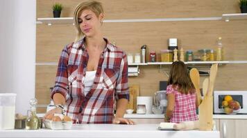 Young daughter helps her mother at the kitchen by bringing a glass bowl in front video