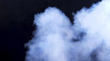 Rising clouds of white abstract smoke over a black background in studio video