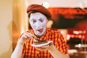 el payaso es comiendo un pastel en un café y su cara es croando. foto