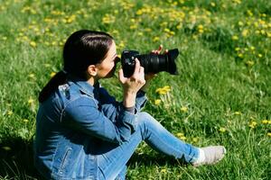 atractivo niña en un prado toma imágenes de flores foto