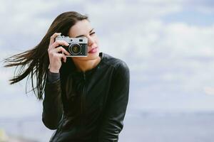 atractivo niña toma imágenes con un antiguo cámara foto