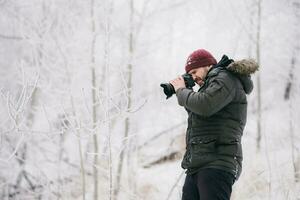 Traveler photographer taking pictures in the winter forest photo