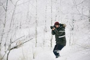 viajero fotógrafo tomando imágenes en el invierno bosque foto