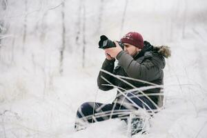 viajero fotógrafo tomando imágenes en el invierno bosque foto