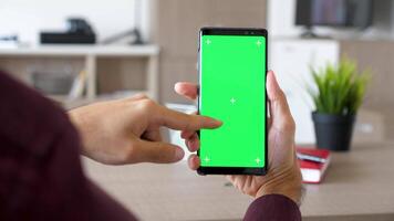 homme main défilement vers le bas sur une téléphone intelligent avec vert écran chrominance moquer en haut. prêt métrage pour votre publicité. juste remplacer le vert écran avec votre métrage ou Photos video