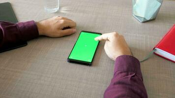 Smartphone with green screen chroma mock up on the table and male hands working on it. Dolly slider 4K footage video