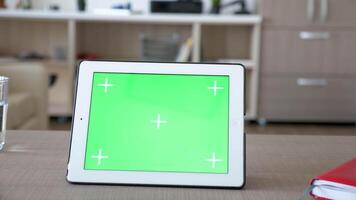 Digital tablet PC with green screen chroma mockup on a table in house living room. Dolly slider 4K footage with parallax effect video