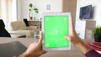 först person punkt av se av manlig händer innehav en digital läsplatta pc i händer med grön skärm krom falsk upp i vertikal placera. dolly reglaget 4k antal fot med parallax effekt video