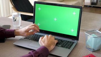 Top view of man in his house working on a laptop with a green screen chroma mock up. Dolly slider 4K parallax footage video