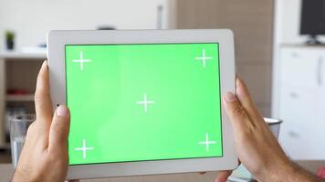 Holding a digital tablet PC with green screen mockup in hands in horizontal mode. Markers available for tracking video