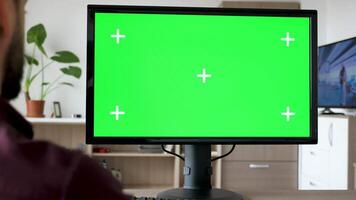 onherkenbaar Mens op zoek Bij modern persoonlijk computer met groot groen scherm chroma bespotten omhoog terwijl de TV in de leven kamer is Aan video