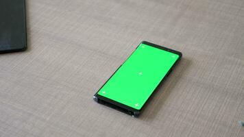 modern smartphone med grön skärm krom falsk upp liggande på de skrivbord. dolly reglaget 4k antal fot video