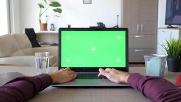 dolly schuif beeldmateriaal van persoon van visie Mens typen Aan laptop toetsenbord met groen scherm chroma bespotten omhoog in zijn huis. parallax effect 4k beeldmateriaal video