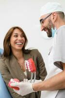 the dentist shows the patient on the example of a human jaw, how teeth are arranged in the mouth photo