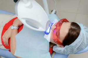 the patient undergoes a procedure for teeth whitening with an ultraviolet lamp photo