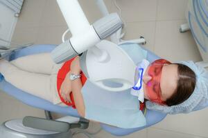 the patient undergoes a procedure for teeth whitening with an ultraviolet lamp photo