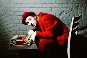 Mime in a red suit prints on a typewriter photo