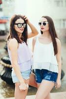 Two beautiful girlfriends pose on the street photo