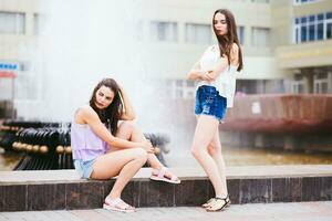 Two beautiful girlfriends pose on the street photo