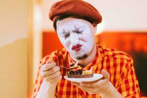 el payaso es comiendo un pastel en un café y su cara es croando. foto